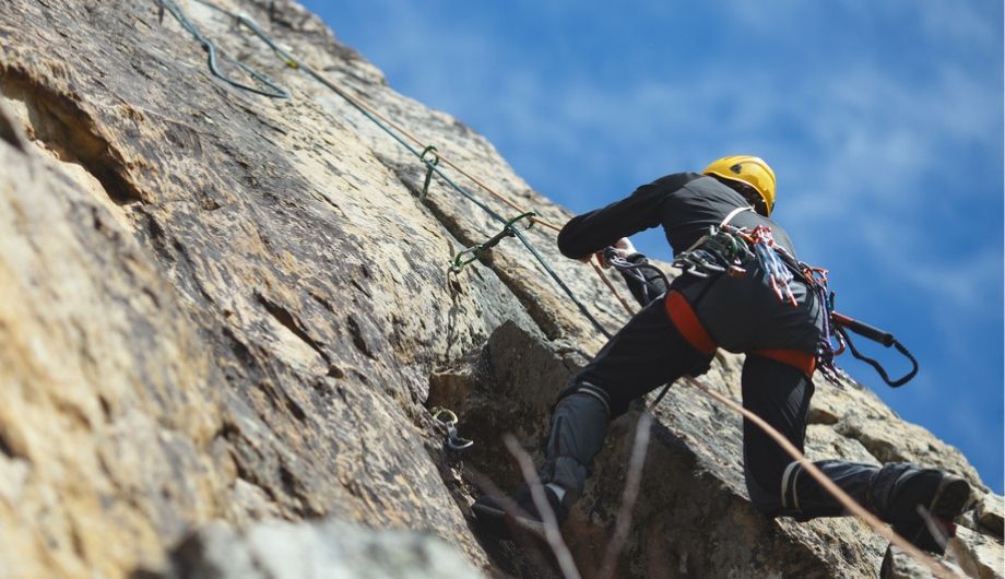 Climber climbs on the rock wall against a blue sky